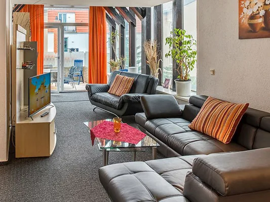 Wohnzimmer der Ferienwohnung De Achterreeg mit großer Couchgarnitur und Terrassentür