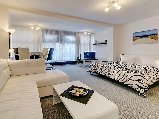 Wohn- und Schlafraum der Warnemünder Stube mit heller Couch und Doppelbett