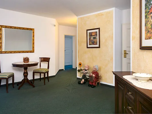 Flur im Hotel Zum Kater mit Spiegel, kleinem Tisch und zwei Stühlen