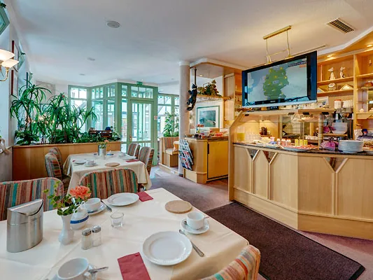 Frühstücksbereich mit Buffet, Pflanzen und Wintergartenfenstern