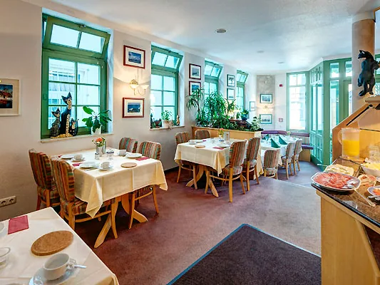 Frühstücksraum im Hotel Zum Kater mit gedeckten Tischen, grünen Fenstern und Buffet