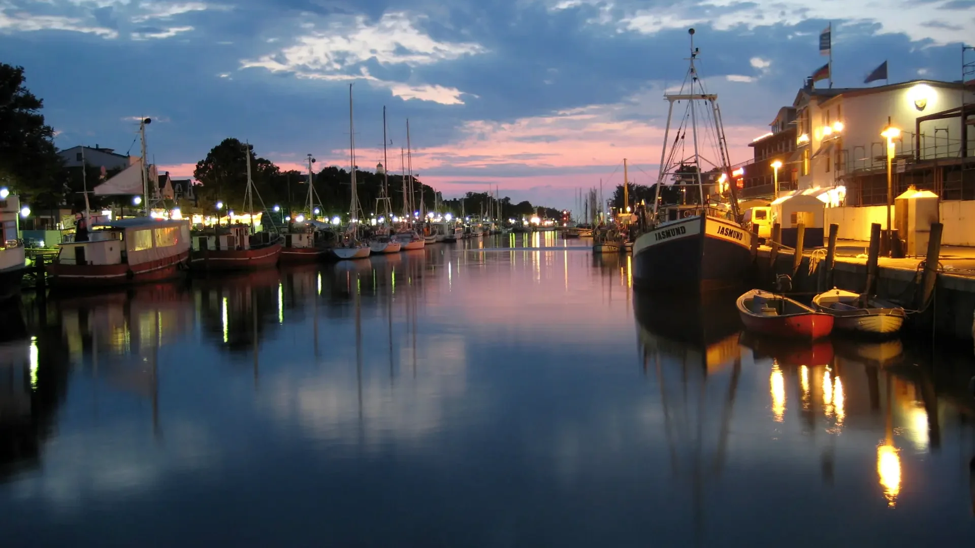 Alter Strom in Warnemünde mit Fischerbooten und Lichtern in der Abenddämmerung