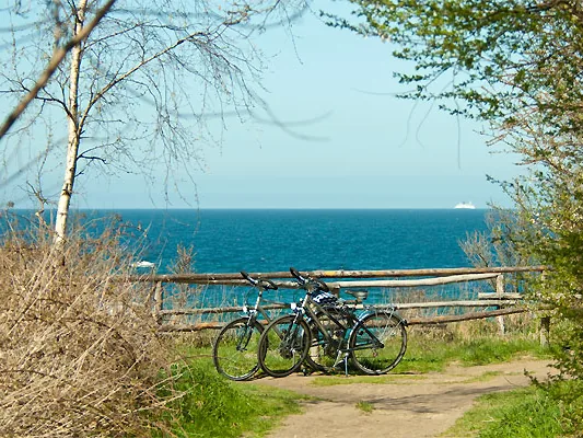 Zwei Fahrräder an einem Holzzaun über der Ostsee an der Steilküste